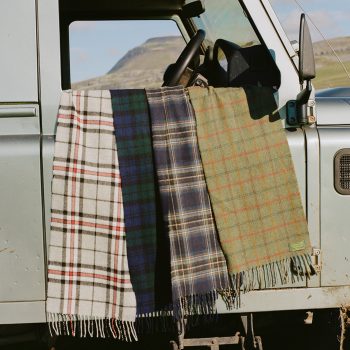 Lambswool tartan scarves draped over window of land rover